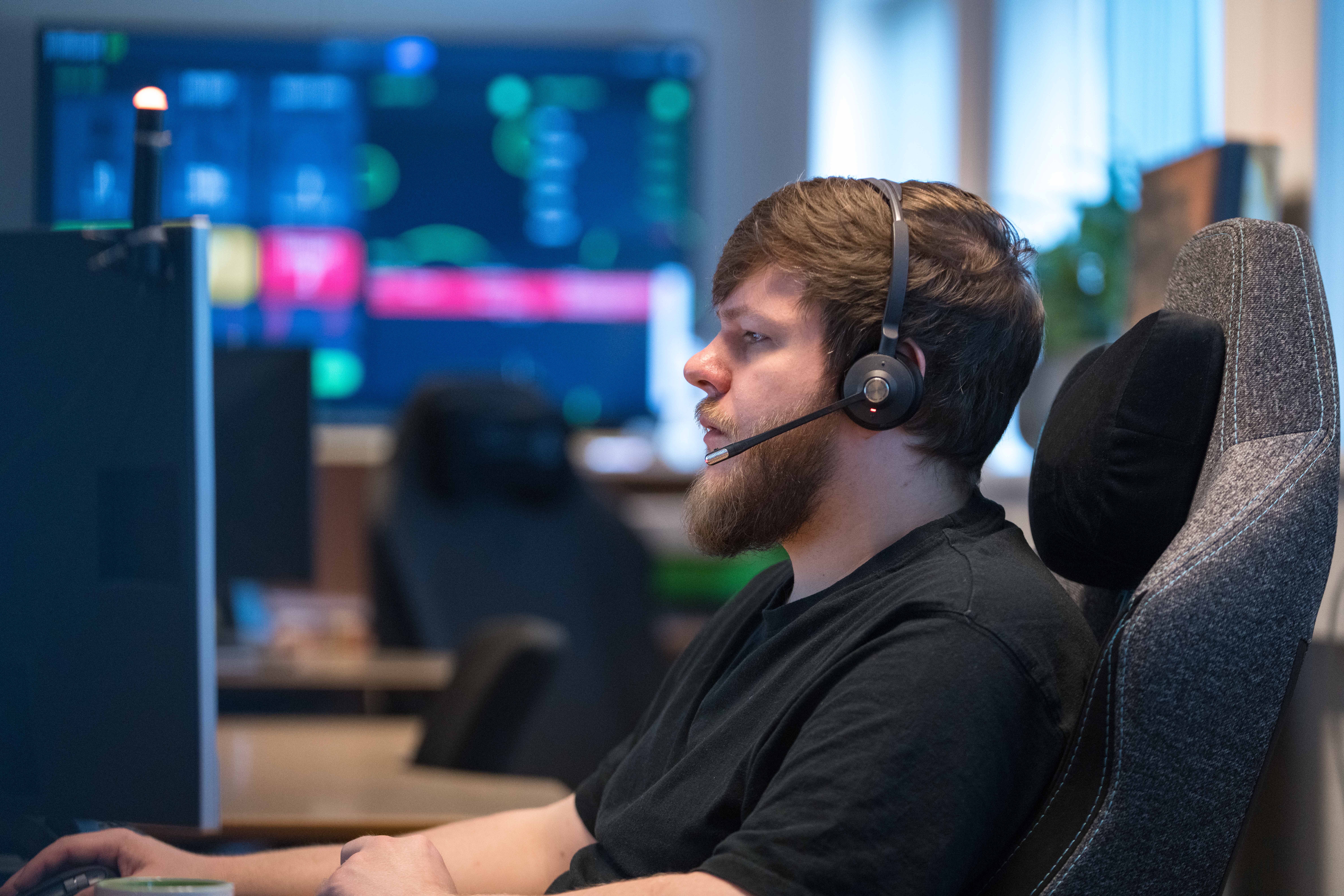 Person sidder foran computerskærm med headset på